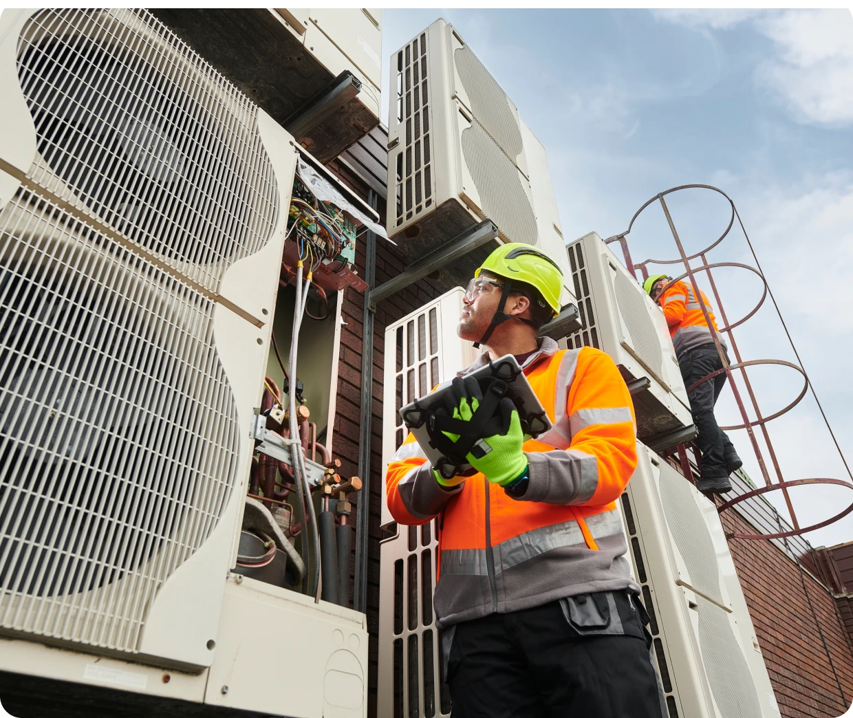 Workers inspecting large outdoor air conditioning units.