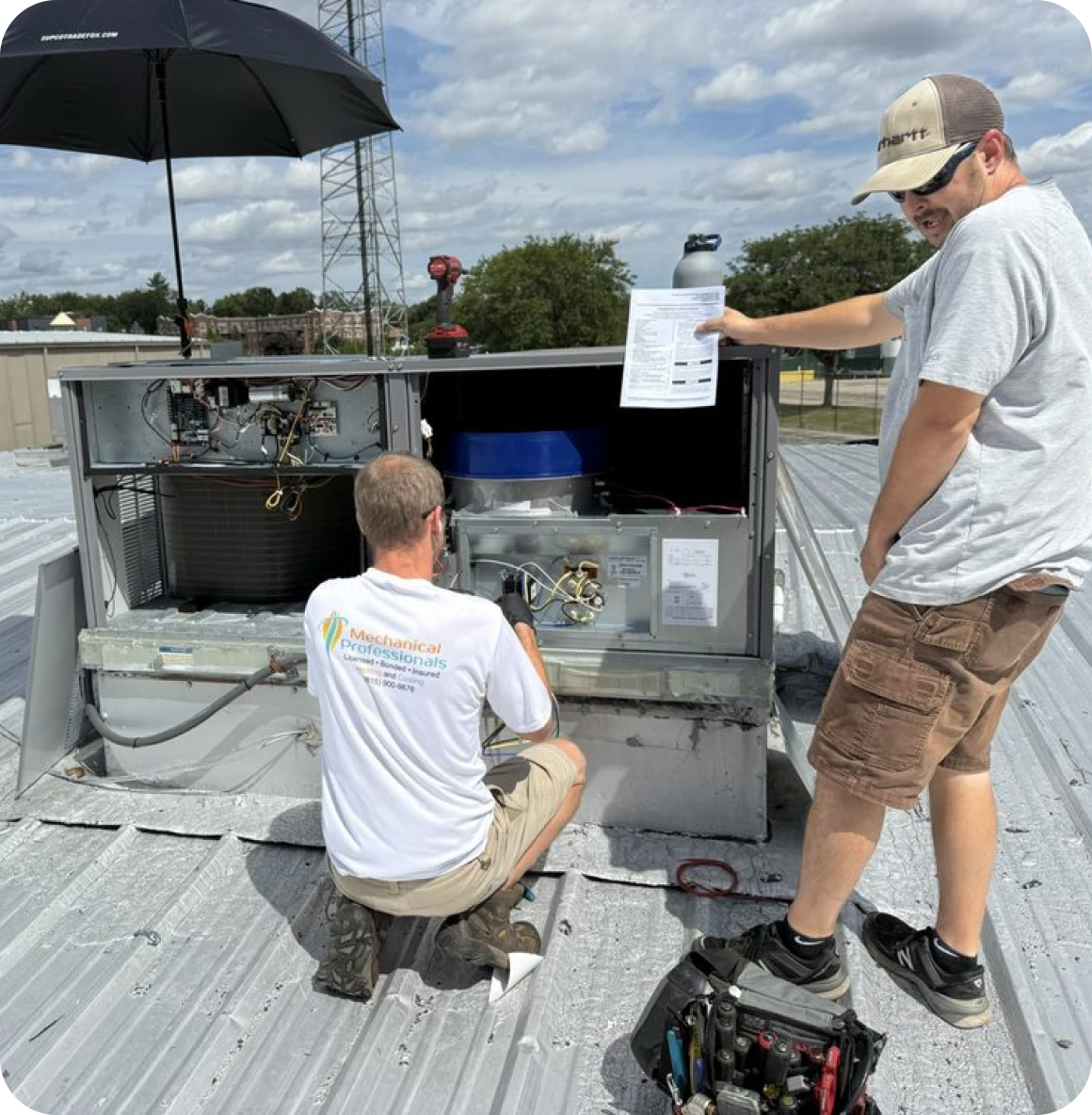 Technicians repairing rooftop air conditioning unit.